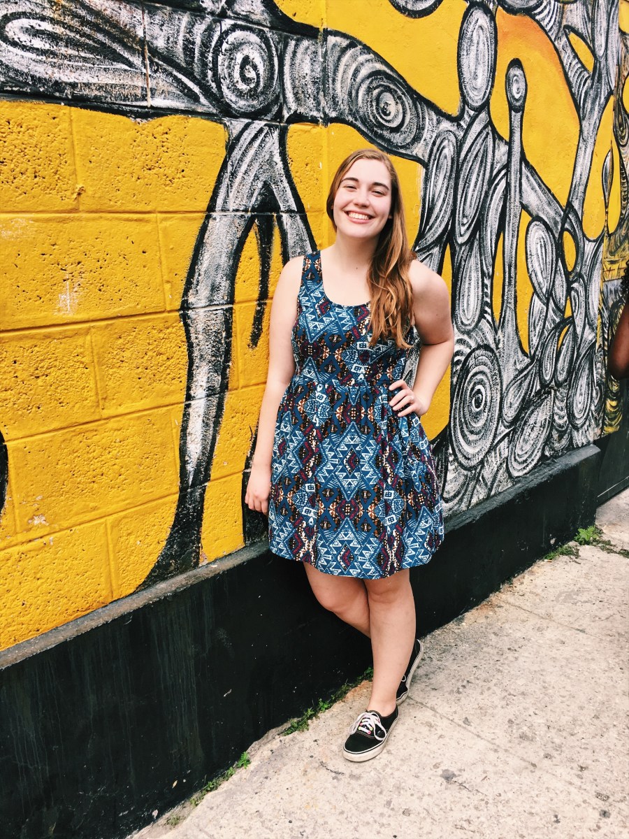 Standing in front of a bright yellow mural in Havana.