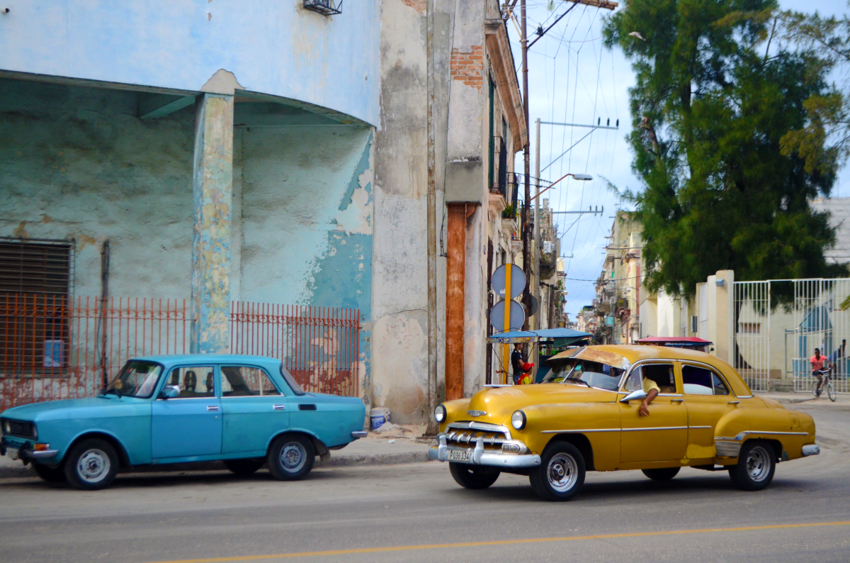 A Soviet car and classic American car next to each other on the street in Havana.