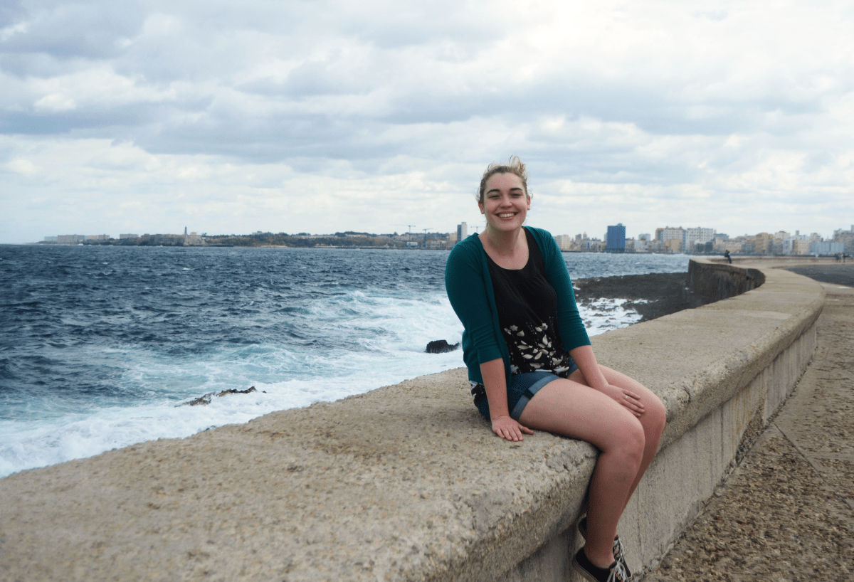 American girl sitting on the edge of the malecon.
